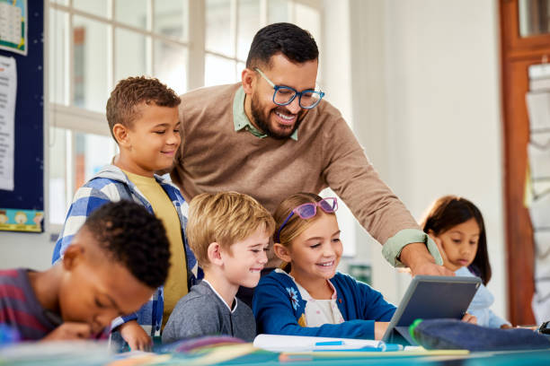 Teacher helping students use a tablet in a classroom