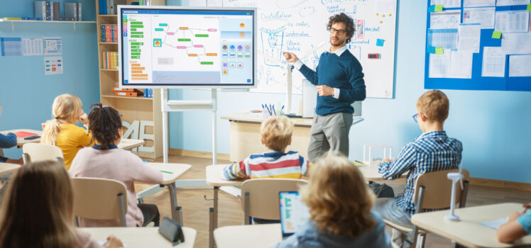 Teacher using an interactive display at the front of a classroom